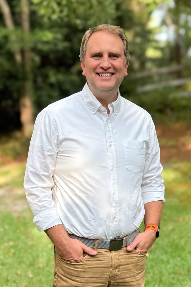 Will Jordan standing outdoors in a white shirt